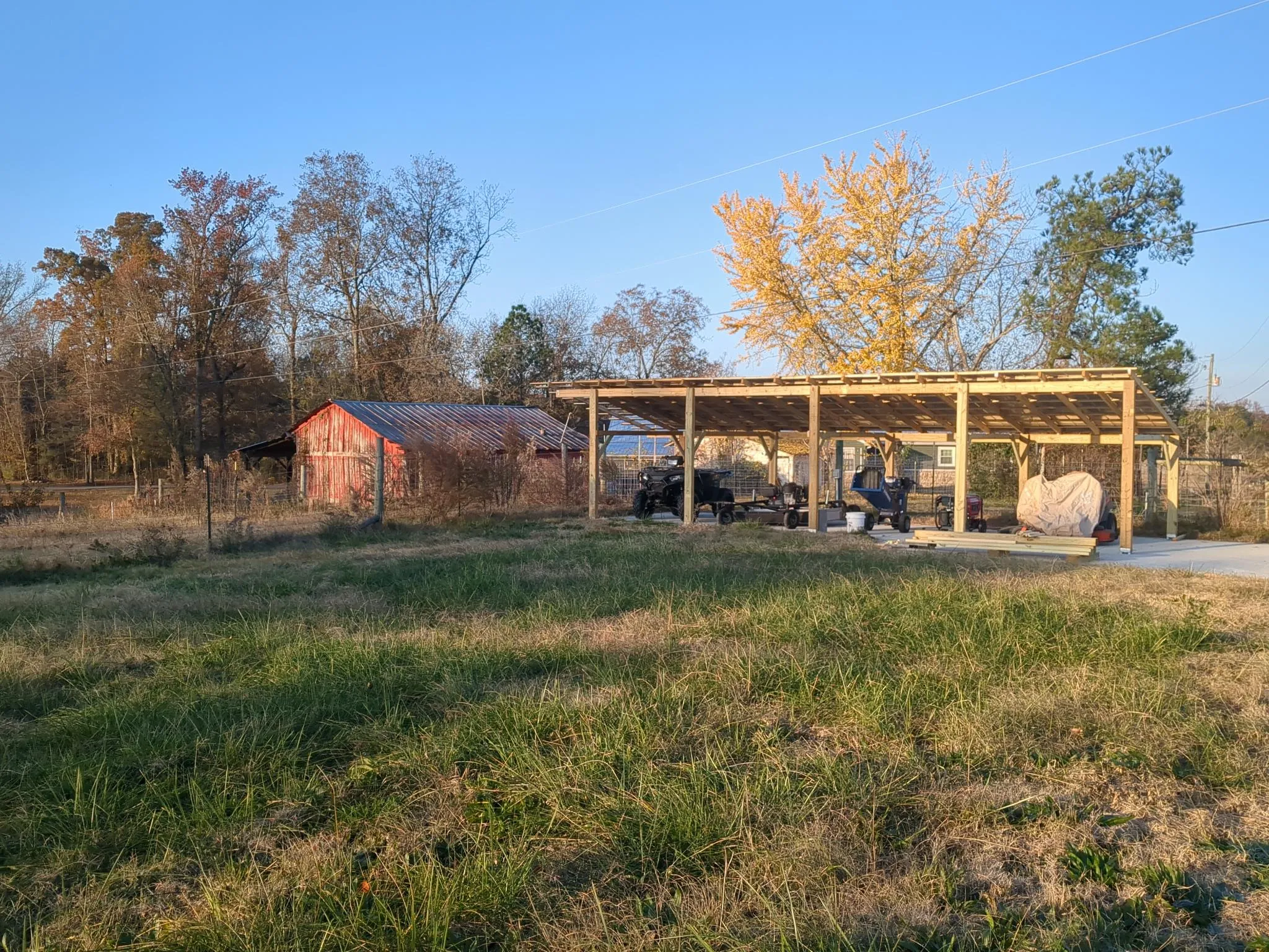 Small equipment parked under a new lean-to carport.